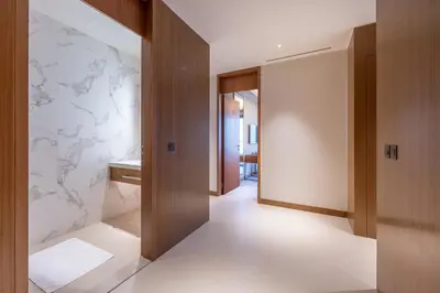 a hallway with white marble walls and wooden doors at 3br on the 49th floor of Address Opera in Dubai
