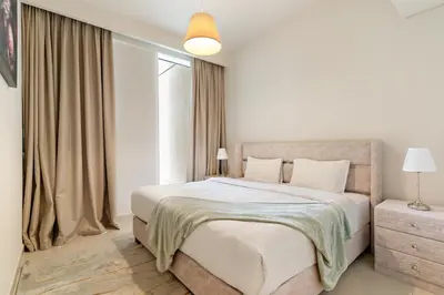 a white bedroom with a large bed and a window at Premium 2BR with Park View in Dubai Creek Harbour in Dubai