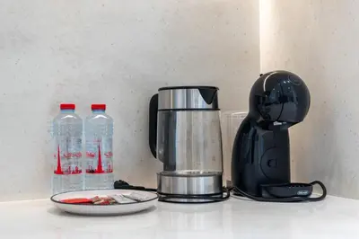 a coffee maker on a counter next to bottles of water at Private pool, Paddle court, Sauna and Hammam - Binghatti Royal in Dubai