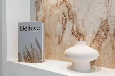 a white vase sitting on a shelf next to a book at Private pool, Paddle court, Sauna and Hammam - Binghatti Royal in Dubai