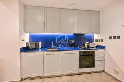 a kitchen with white cabinets and blue counter tops at Stylish Studio with views of pool & Burj Khalifa in Dubai
