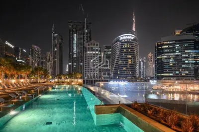 a swimming pool with a city skyline at night at Stylish Studio with views of pool & Burj Khalifa in Dubai