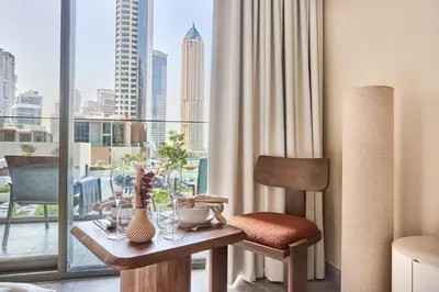 a table and chair in a room with a window at Frank Porter - Peninsula One in Dubai