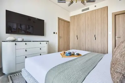 a bedroom with a bed with a tv and a dresser at Frank Porter - Peninsula One in Dubai