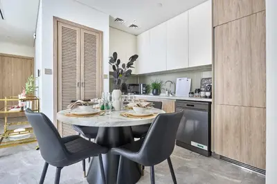a kitchen with a table and chairs in a room at Frank Porter - Peninsula One in Dubai