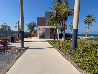 a sidewalk with palm trees in front of a building at Frank Porter - La Voile 3, La Mer in Dubai