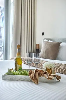 a tray of grapes and wine glasses on a bed at Frank Porter - J One Tower, Business Bay in Dubai