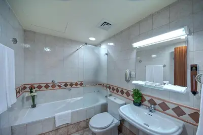a bathroom with a tub and a toilet and a sink at Al Manar Grand Hotel Apartment in Dubai