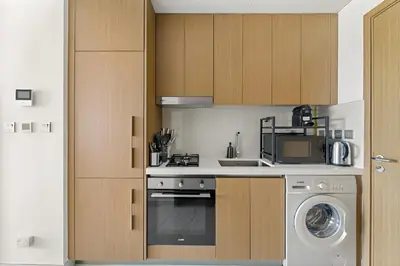 a kitchen with a washing machine and a washer at Elegant Retreat Studio in Azizi Mirage in Dubai