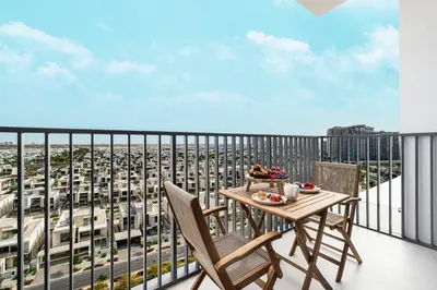 a balcony with a table and chairs and a view of a city at Bright & Stylish 1BR in Park Field, Dubai Hills Estate in Dubai