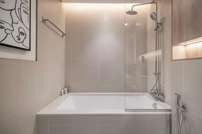 a bathroom with a bath tub with a glass door at Bright & Stylish 1BR in Park Field, Dubai Hills Estate in Dubai