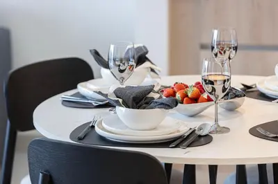 a table with glasses of wine and a bowl of fruit at Bright & Stylish 1BR in Park Field, Dubai Hills Estate in Dubai