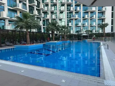 a large blue swimming pool in front of a building at Stylish Studio near Downtown with pool in Dubai