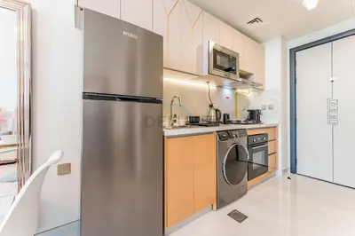 a kitchen with a stainless steel refrigerator and a dishwasher at High-Floor Studio with Views of Miracle Garden and Community, Near Dubai Top Attractions, Skyz by Danube, Arjan by Deluxe Holiday Homes in Dubai