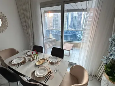 a dining room table with a white tablecloth and chairs at Premium 2BR Marina View Apartment in Dubai Marina in Dubai
