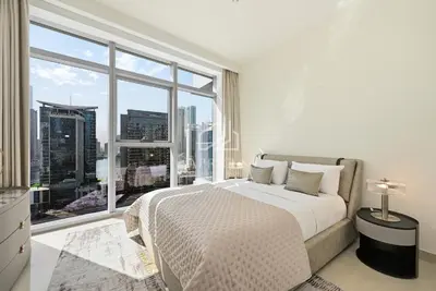 a bedroom with a bed and a large window at Luxury Urban Living at Imperial Avenue, Downtown in Dubai