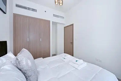 a bedroom with a white bed with two towels on it at Bloomfields Cozy 1BR Azizi Riveria 47 in Dubai