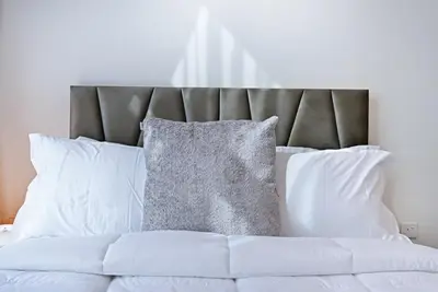 a bed with white pillows and a gray headboard at Bloomfields Cozy 1BR Azizi Riveria 47 in Dubai