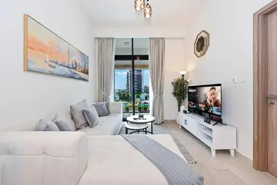 a white living room with a white couch and a tv at Bloomfields Cozy 1BR Azizi Riveria 47 in Dubai
