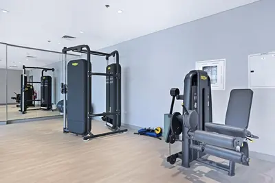 a gym with a row of tread machines in a room at Bloomfields Cozy 1BR Azizi Riveria 47 in Dubai
