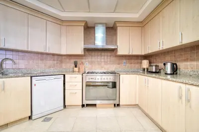 a kitchen with white appliances and wooden cabinets at Shoreline 14, Al Hallawi, Palm Jumeirah - Mint Stay in Dubai