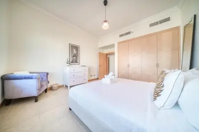 a bedroom with a large white bed and a chair at Shoreline 14, Al Hallawi, Palm Jumeirah - Mint Stay in Dubai