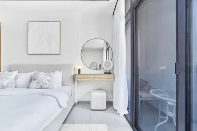 a bedroom with a bed and a mirror and a desk at Elegant 1BR Apartment in Ikarus, Dubai Production City in Dubai