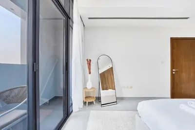 a bedroom with a white bed and a mirror at Elegant 1BR Apartment in Ikarus, Dubai Production City in Dubai