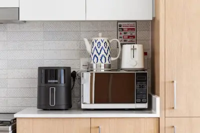 a microwave and other appliances on a kitchen counter at Luxury 2BR with Burj Khalifa View in Port Rashid in Dubai