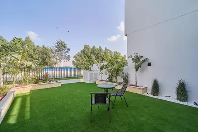 a patio with a table and chairs on a green lawn at Premium 3 Bedroom Townhouse in DAMAC Lagoons in Dubai