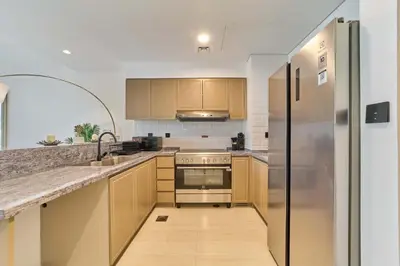 a kitchen with wooden cabinets and a stainless steel refrigerator at Premium 3 Bedroom Townhouse in DAMAC Lagoons in Dubai