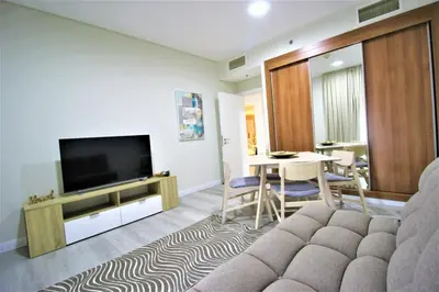 a living room with a television and a table with chairs at Modern 2-Bedroom Apartment with JBR and Marina view on High floor in Dubai