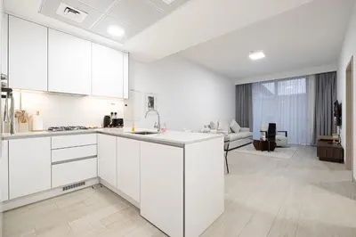 a kitchen with white cabinets and a living room at Restay Homes at Luma22 West Tower in Dubai