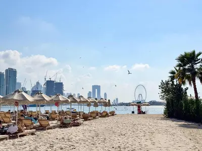 a beach with chairs and umbrellas and a city at PVH - Seven Palm - Modern Studio with Beach Access near Palm Jumeirah Mall in Dubai