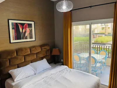 a bedroom with a bed and a balcony with a table and chairs at Remraam Holiday Home Dubai in Dubai