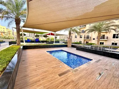 an outdoor swimming pool with a large umbrella and a building at Remraam Holiday Home Dubai in Dubai