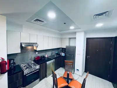 a kitchen with black and white appliances and a table and chairs at Remraam Holiday Home Dubai in Dubai