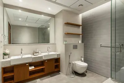 a bathroom with two sinks and a toilet and a mirror at CitiHome - Spacious 2BR - Park Gate Residences in Dubai