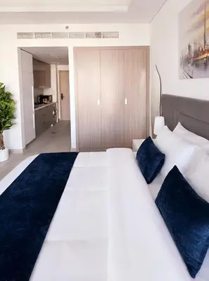 a bedroom with a large white bed with blue pillows at Modern Deluxe Studio in Dubai in Dubai