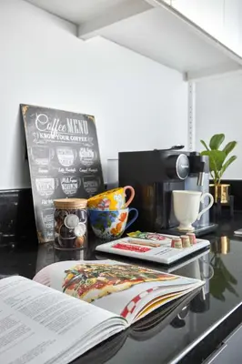 a kitchen counter with an open book and a coffee machine at Frank Porter - Damac Maison Prive in Dubai