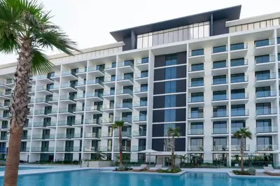 an exterior view of a building with a swimming pool and palm trees at Binghatti Phoenix Luxe 1BR with Tranquil Pool View in Dubai