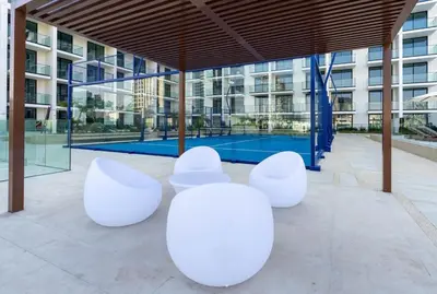 a group of white chairs in front of a building at Binghatti Phoenix Luxe 1BR with Tranquil Pool View in Dubai