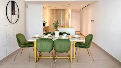 a dining room with a table and green chairs at Stylish 2 Bed with full marina view on high floor in Dubai