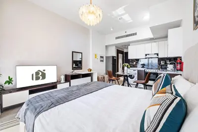 a white bedroom with a bed and a kitchen at BLVD Modern Stay in Jewelz -Balcony Pool & Gym in Dubai