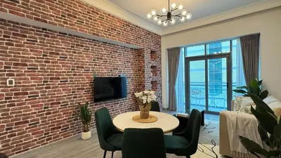 a living room with a brick wall and a table and chairs at 1BDR Large Living Room Nearby Metro in Dubai