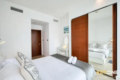 a white bedroom with two beds and a mirror at Spectacular Marina Views Luxurious Two Bedroom in Dubai