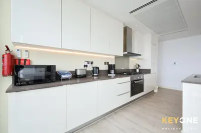 a kitchen with white cabinets and black appliances at Spectacular Marina Views Luxurious Two Bedroom in Dubai
