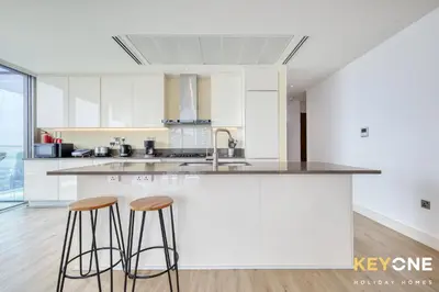 a kitchen with white cabinets and two bar stools at Spectacular Marina Views Luxurious Two Bedroom in Dubai
