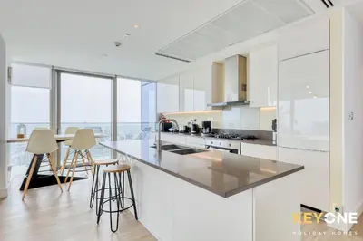 a kitchen with white cabinets and a counter with stools at Spectacular Marina Views Luxurious Two Bedroom in Dubai