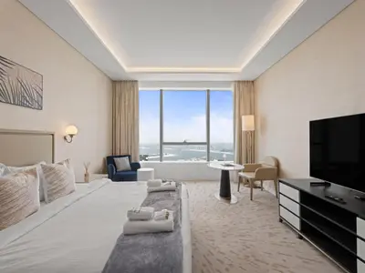 a hotel room with a large bed and a flat screen tv at Sunset Bliss Elegant Palm Island Studio in Dubai